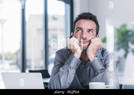 Businessman sitting in office, thinking Stock Photo