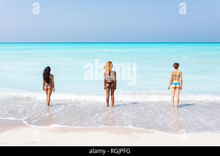 Young women standing at the sea, looking at distance, rear view Stock Photo