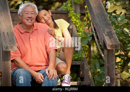 Portrait of a smiling young girl sitting with her grandfather. Stock Photo