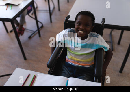Disable schoolboy looking at camera in classroom Stock Photo