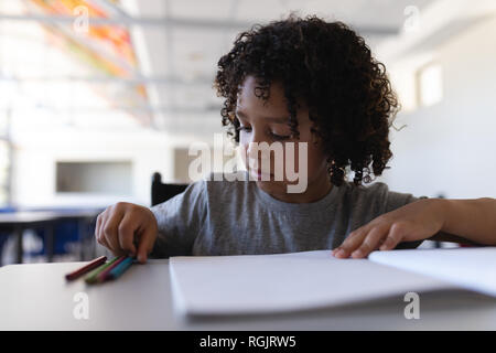 Schoolboy studying at desk in classroom Stock Photo