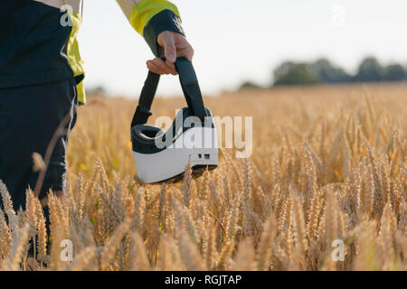 Close-up of man in protective workwear and VR glasses in a field Stock Photo