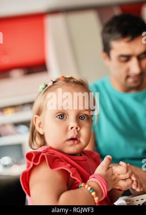 Portrait of blond little girl with her father in the background Stock Photo