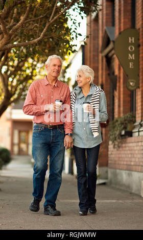 Mature couple handing hands, walking after getting a coffee. Stock Photo