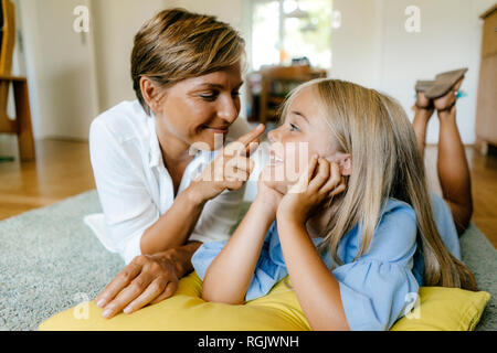 Happy mother and daughter lying on the floor at home Stock Photo