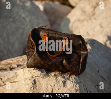 Formia, Italy - April 11, 2017: Louis Vuitton women's handbag on a rock in the sunlight. Stock Photo