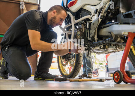 Mechanic working on motorcycle in workshop Stock Photo