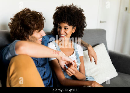 Happy couple sitting on couch talking Stock Photo