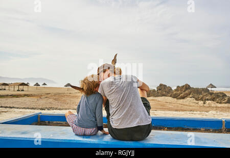 Chile, Arica, mother sitting with son on wall on the beach Stock Photo