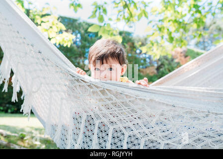 Spain, Baby girl relaxing in a hammock in the garden in the summer Stock Photo