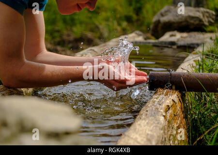 Germany, Upper Bavaria, Chiemgau, Young man refreshing at a fountain Stock Photo