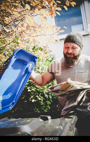 Portrait of man recycling waste paper in paper bank Stock Photo