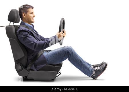 Full length profile shot of a young man in a car seat with a fastened seat belt holding a steering wheel isolated on white background Stock Photo