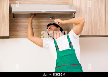 Young contractor repairing air-conditioner in kitchen Stock Photo