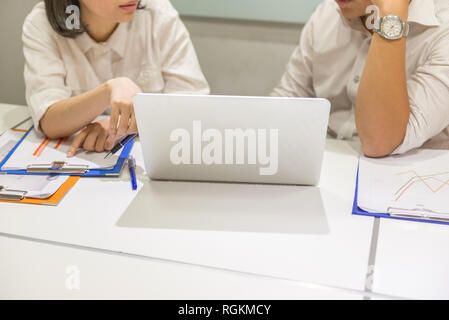 Two business employees discuss about work on laptop Stock Photo