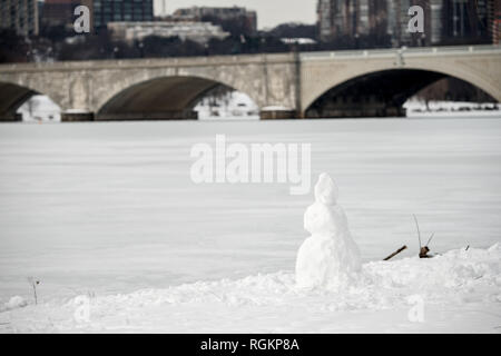 WASHINGTON, DC, United States — The Arlington Memorial Bridge spans a frozen, snow-covered Potomac River connecting Washington DC with Arlington, Virginia. The commercial buildings of the Rosslyn district rise in the distance on the Virginia shore. The neoclassical bridge serves as a major crossing point between the two jurisdictions. Stock Photo