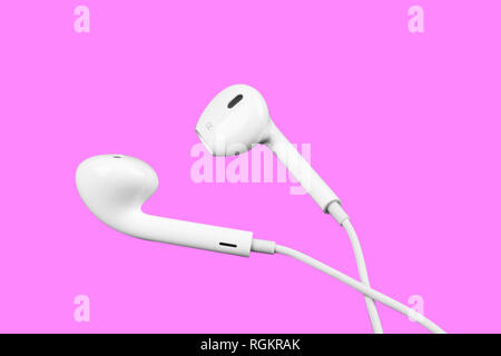 White little headphones isolated on purple background. Earphones isolated on black background. Stock Photo