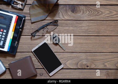 Top view of gentlemen accessories on wood background. Blank space smartphone, wallet, belt, pen, glasses, car key, planner and necktie on wood. Flat l Stock Photo