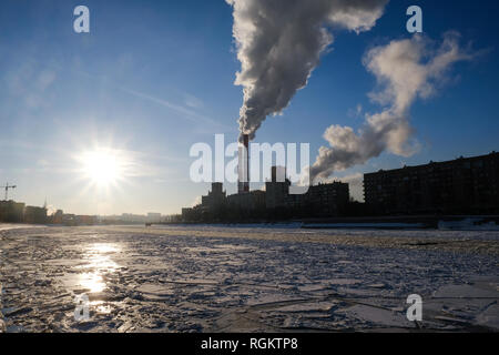 Smoke from heating system chimney close to the frozen Moscva river in Moscow during winter Stock Photo