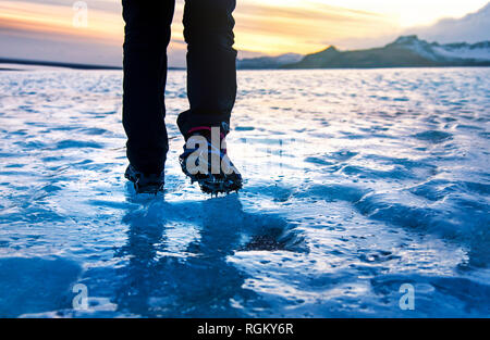 Person walking on glacier ice surface wearing crampons low angle Stock Photo