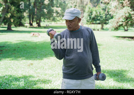 old asian man using dumbell in the park Stock Photo