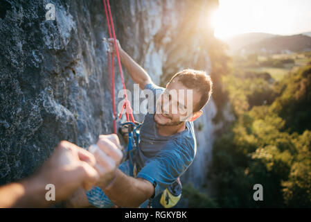 Man giving fist five during rock climbing Stock Photo