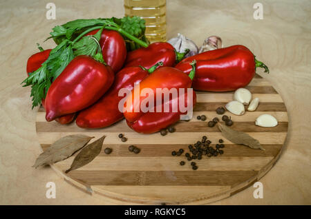 Red bell peppers,celery, garlic and spices on a wooden chopping Board with a bottle  of olive oil on a wooden table Stock Photo