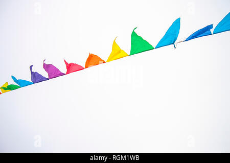 Colorful multicolored triangular flags, isolated on a white background, hang on a rope and flutter in the wind. Holiday decoration, carnival, festival Stock Photo