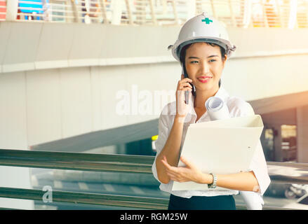 Engineer woman talking on cell phone and carry white floder data work Stock Photo
