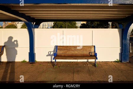 Photographers shadow in a picture of a seaside bench early on a winter morning Stock Photo