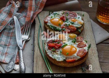 Toasts with eggs and tomatoes on cutting board Stock Photo