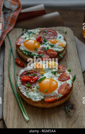 Toasts with eggs and tomatoes on cutting board Stock Photo