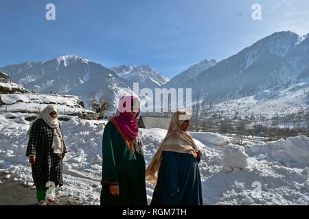 Kashmiri women seen walking through a snow covered road on a sunny winter day in Gagangir area of district Ganderbal, about 80kms from Srinagar, Indian administered Kashmir. Kashmir is the northernmost geographical region of the Indian subcontinent. It is currently a disputed territory, administered by three countries: India, Pakistan and China. Stock Photo