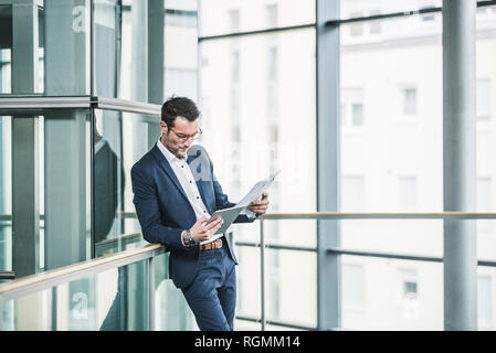 Businessman standing in office building, using digital tablet Stock Photo
