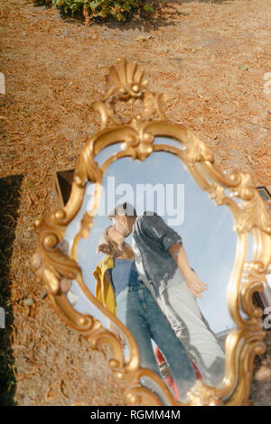 Affectionate young couple kissing reflected in vintage mirror Stock Photo