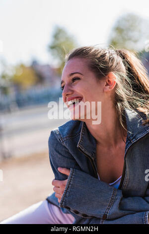 Portrait of laughing young woman outdoors Stock Photo