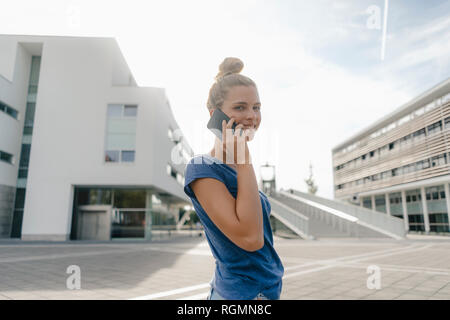 Netherlands, Maastricht, smiling young woman on cell phone in the city