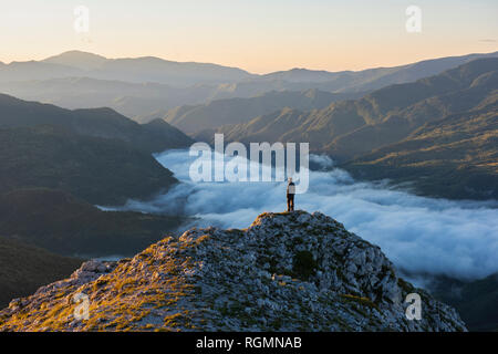 Italy, Umbria, Sibillini National Park, hiker standing on viewpoint at sunrise Stock Photo