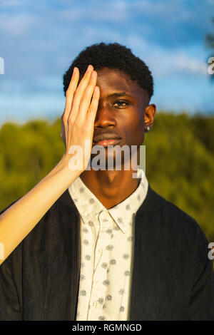 Hands covering eyes of a young black man Stock Photo