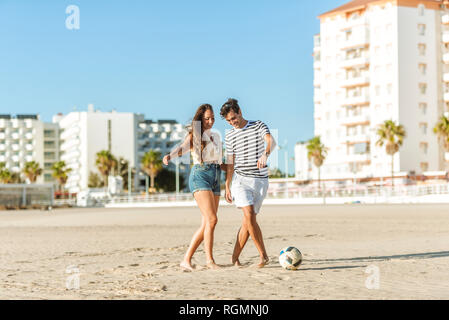 Happy young couple playing soccer on the beach Stock Photo