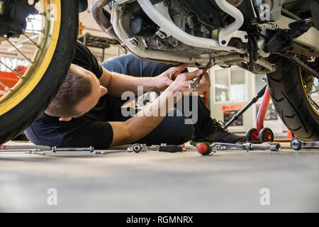 Mechanic working on motorcycle in workshop Stock Photo