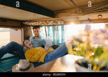 Happy young couple looking at tablet inside camper van Stock Photo
