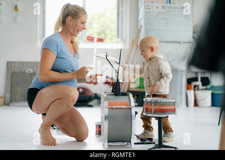 Happy pregnant mother with toddler son playing toy drums