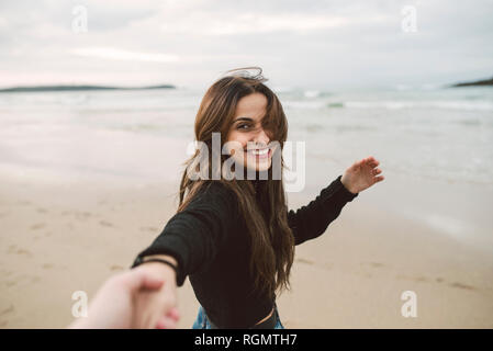 Portrait of smiling young woman holding hands on the beach Stock Photo