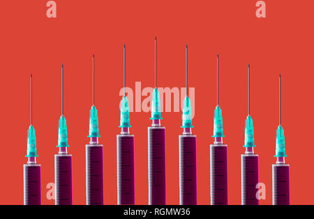 Multiple syringes organized in a pattern over orange background Stock Photo