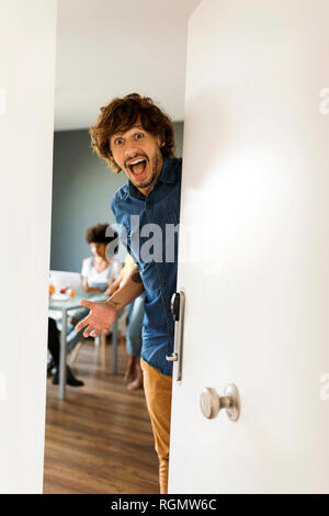 Portrait of surprised man with friends in background opening the door Stock Photo