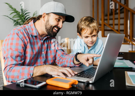 Father and son using laptop together Stock Photo