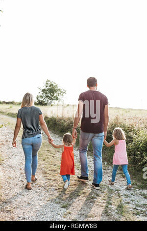 Family walking hand in hand in field, rear view Stock Photo - Alamy
