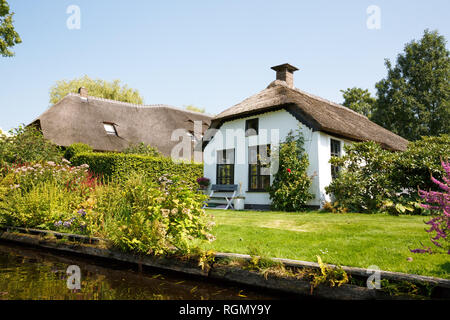 The thatched roof houses with beatiful garden in fairytale village Giethoorn in The Netherlands. Stock Photo