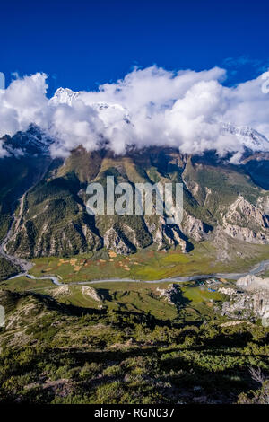 Aerial view on the agricultural countryside of the Upper Marsyangdi valley, cloudy alpine landscape of the Annapurna group in the distance Stock Photo